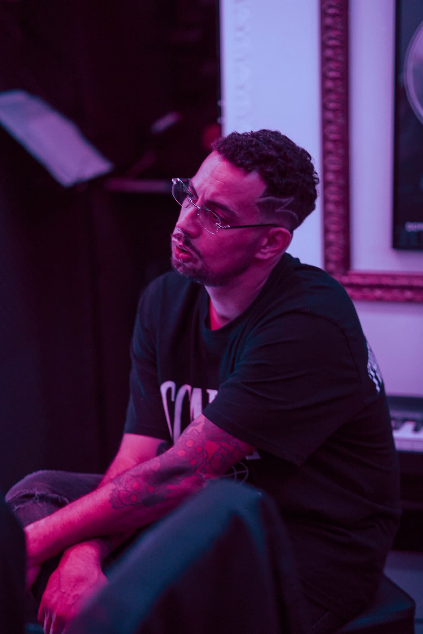 Davide Del Carmen seduto in un ambiente illuminato di magenta e viola